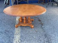 Full view of round maple pedestal coffee table outdoors showing entire table and base.