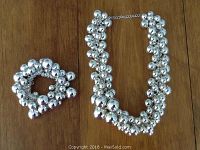 Photo showing the silver-tone multi-bead necklace next to the matching elastic bracelet on a wooden surface.