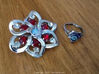 Both items shown on wood surface; ring and flower-shaped brooch, both featuring Canadian Air Force insignias and stones.