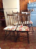 Four pine kitchen chairs arranged together showing general condition, floral cushions, and wood finish.