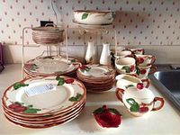 Full array of dinner plates, cups, saucers, serving bowls and accessories displayed on counter