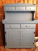 Front view of Williamsburg Blue painted wood dry sink with three small drawers on top, two larger drawers in the middle, and a cabinet base with double doors.