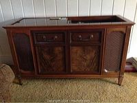 Front view of the vintage Magnavox console stereo with wooden cabinetry, fabric speaker covers, and two drawers visible.