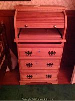 Roll top desk with curved top, pull-out writing surface and drawers underneath, light wood finish with dark ornate drawer handles.