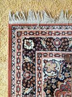 Close-up photo showing the fringe edge and detailed border pattern of one rug, highlighting colors of rust, black, cream, and floral motifs.