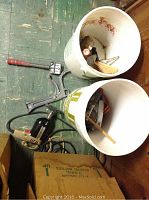 Photo showing two white buckets filled with assorted hand tools and power tools including an Ingersoll Rand double insulated sander