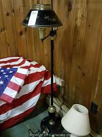 Full view of standing lamp with black and gold floral design next to small lamp with white lampshade.