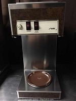 Front view of the coffee machine showing control panel with start button and two toggles.