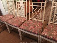 Four bamboo style dining chairs with white painted wood frames and floral upholstered seats arranged in a row showing front and side views.