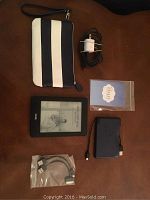 Layout of all items included in the lot: Kindle, wristlet case, charger, cables, power bank, and adapters.