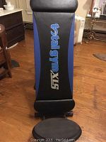 Top view of the padded backrest of the Total Gym XLS with branding and blue side panels on hardwood floor.