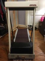 Treadmill showing front view with missing side panels and black tread belt.