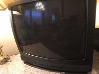 Front view of black Zenith CRT television showing curved screen and integrated front surround speaker grille below it.
