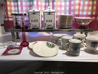 Assorted dinnerware and decorative serving ware including plates, cups, porcelain containers labeled CAFE and CHA, and a decorative bowl.
