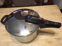 Fagor Multi-Rapid pressure cooker with lid and electronic handle visible from the top on a wood surface