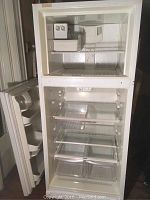 Front view of white Kenmore refrigerator/freezer with freezer door open, showing ice machine compartment and shelving.