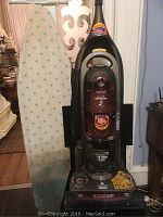 Photo showing the Bissell Lift-Off Deluxe vacuum cleaner next to the ironing board covered with a white and green patterned fabric.