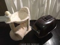 Photo showing the cat tree and covered litter box with scooper side by side on dark wood floor.