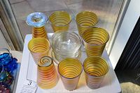 Top-down view of hand-blown yellow glasses with spiral decoration and clear bowls grouped on a white surface.