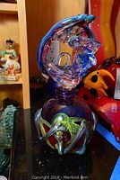 Photo of a colorful lidded decorative glass container with abstract swirls and glass finial lid