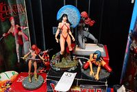 Photo of five female Comics and collectible figures showing front view of Vampiella porcelain figure, Red Sonja variants in red and grey costumes, Electra half figure, and Marka figure, some boxes visible.