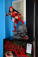 Full view of Elektra figure on display base with character name and box underneath
