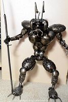 Single large welded metal humanoid insect warrior holding a spear
