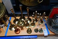 Photo showing all items including brass candle holders, brass teapot, two small Swedish candle holders, brass vase and copper vase on a wooden surface.