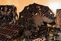 Close-up of batik wax stamps showing intricate floral and leaf carvings in wood.