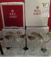 Four Royal Albert Old Country Roses wine glasses with floral design and gold rim, displayed in front of original Royal Albert boxes