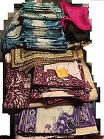 Stack of brightly colored batik dyed linens in teal, maroon, purple, brown, and bright pink folded and stacked