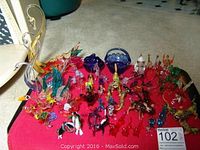 Overview of over 65 colorful hand blown glass animals arranged on a red cloth, including swans, horses, birds, and various animal shapes with glass basket and hens dish visible.