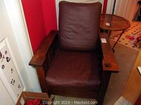 Front view of Stickley style Arts and Crafts wooden armchair with new brown leather seat and back cushions, showing slatted wood arms and solid frame.