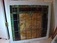 Full view of the stained glass window in a white wooden frame showing overall design and condition.