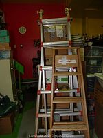 Little Giant aluminum ladder system with red safety components alongside Werner wooden ladder indoor storage setting.