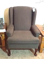 Front view of the Best Home Furnishings Queen Anne wing back chair showing Basil green upholstery and dark cherry wood legs.