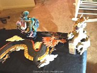Photo showing two ceramic dragon sculptures beside the metal dragon wall art on a carpeted floor, illustrating sizes and details.
