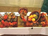 Photo showing entire Thanksgiving decorative set arranged on white tablecloth, featuring ceramic turkey, metal leaf platter, cornucopia with gourds, and fall garland.