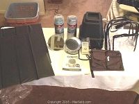 Full lot showing bed risers, Conair soothing sounds system, alarm clock, travel pouches, furniture pads, and cooling towels spread out on table.