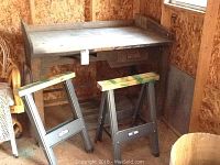 Vintage wooden work bench with two metal saw horses in a shed