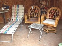 Rattan chairs with aluminum chaise lounge and metal patio table shown in backyard shed.