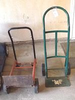 An overview photo showing two metal hand trucks side by side: a red 4Wheel Wonder Cart on the left and a green standard hand truck on the right. Both show signs of use and wear.