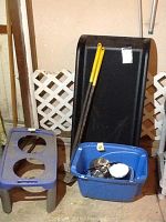Wide view showing raised dog feeding station, raised cat feeding station with bowls, a large black pet ramp, and a blue storage bin containing metal bowls and other items.