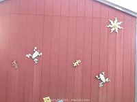 Wide view of a red wood panel wall with assorted metal art figures of frogs, lizards, gecko and sun decor mounted for garden or patio decor.