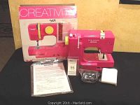 Full view of Janome 525B sewing machine with box, manual, foot pedal and power adapter on black surface