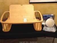 Wooden bed tray with side compartments and adjustable reading surface placed on a black cloth.