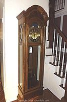Full view of oak grandfather clock in interior setting showing overall condition, case and glass panels.