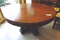 Full view of round table top and black cross-shaped pedestal base