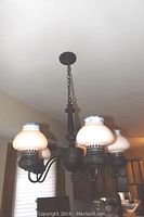 Vintage five arm dark metal ceiling chandelier hanging from the ceiling with frosted glass shades and blue painted borders.