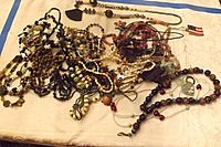 Photo showing a grouped collection of multiple beaded and chain necklaces in a variety of colors and materials including wood, plastic, and metal.